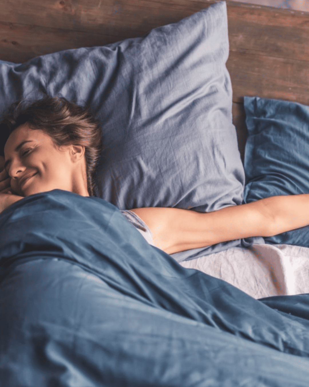 Person sleeping comfortably under breathable wool duvet set with blue organic cotton cover — temperature-regulating bedding for cooler, deeper sleep.